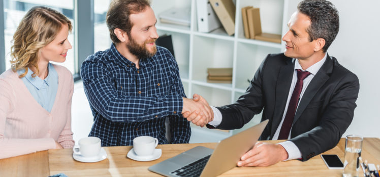 portrait of smiling lawyer and client shaking hands at meeting in office