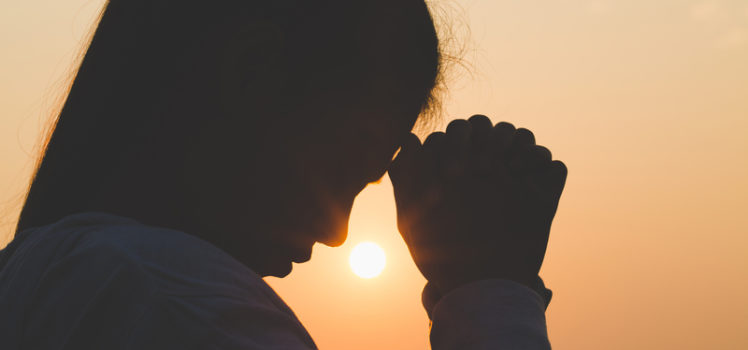 Young woman praying in the morning, Hands folded in prayer concept for faith, spirituality and religion